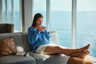 Frau entspannt auf dem Sofa der Ruhepol Bar – © TUI Cruises