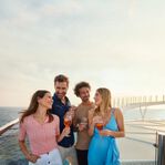 Freunde mit Drinks auf dem freischwebenden Umlauf – © TUI Cruises