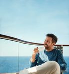 Mann genießt Kaffee auf dem Balkon der Kabine – © TUI Cruises